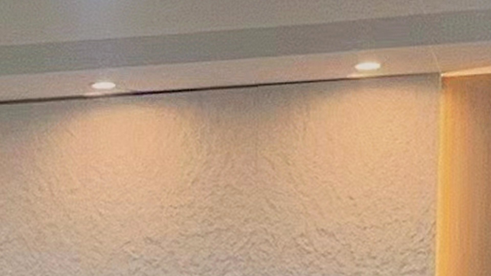 Interior wall in a white MCM finish, raked by concealed cove lighting
