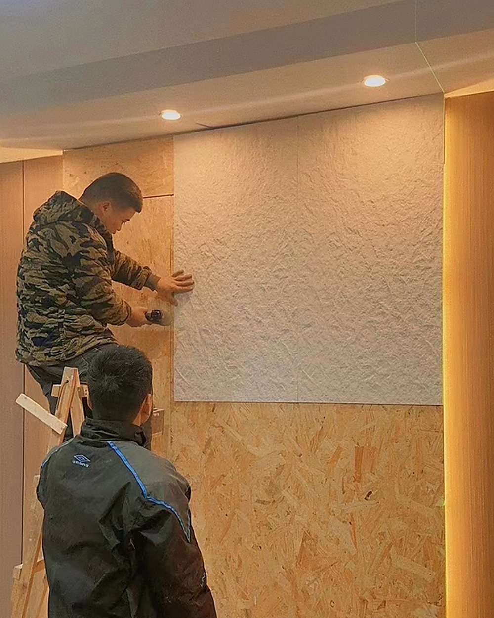 Two installers bonding a MCM sheet to an interior wall